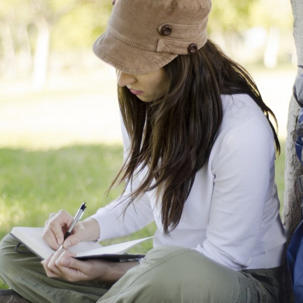 Young beautiful woman writing on a journal about her hiking trip